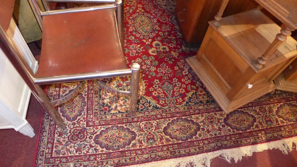 A Persian design carpet with floral design on a red field with spandrels surrounded by one frieze