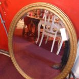 An early C20th looking glass with oval bevelled plate in carved gilt wood frame and a smaller