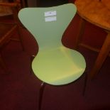 A set of three green designer chairs raised on chromed supports