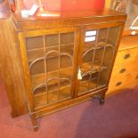 An oak bookcase fitted pair of glazed panel doors and raised on turned stretchered supports