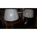 A pair of cut glass table lamps with white silk shades