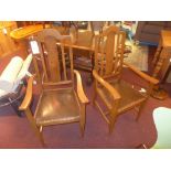 A pair of oak open elbow chairs with pad seat and raised on tapering supports