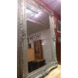 A large wall mirror the rectangular bevelled plate within ornate swept silvered frame