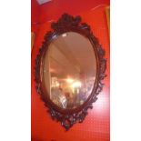 A carved mahogany wall mirror with oval plate