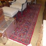 A hand knotted Persian carpet the red ground with allover stylized decoration within multi border