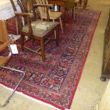 A hand knotted Persian carpet the red ground with allover stylized decoration within multi border