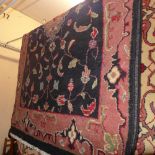 A hand made Persian carpet with a terracotta medallion on a midnight blue field surrounded by a
