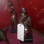 A pair of silvered porcelain models of a woman and a cheetah