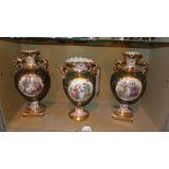 A set of three C19th twin handled vases decorated with pictoral reserves and heightened in gilt