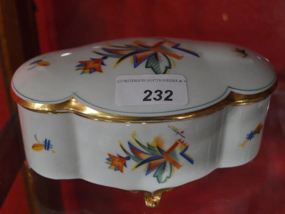 A German Art Deco porcelain box and cover decorated with polychrome geometric motifs raised on