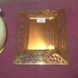 An Arts and Crafts brass mirror with pierced detail and a rectangular bevelled plate and