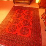 A hand made Afghan carpet the dark red field with geometric black motifs in a triple border