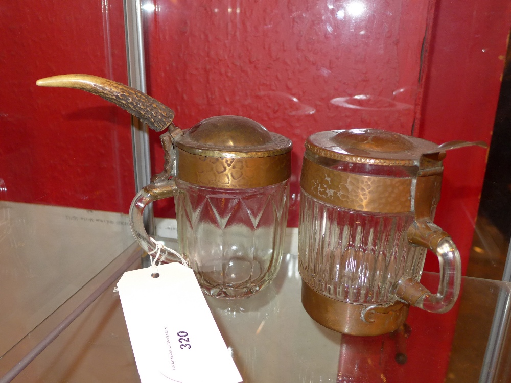 A moulded glass and planished copper lidded tankard and a similar (2)