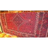 A Persian rug with a triple pole medallion on a midnight blue and red field surrounded with two