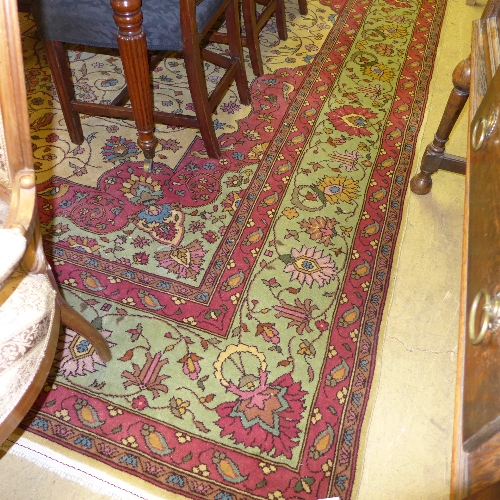 A large hand knotted Persian carpet with floral design on green field