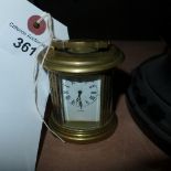 A brass oval miniature mantle clock