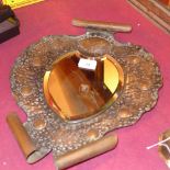 An Arts and Crafts planished wall mirror with bevelled detail and a shield form bevelled plate