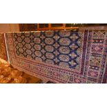 A Persian Bokhara style carpet the dark blue field with repeating motifs in gold in a triple border