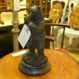 A bronzed figure of a bear eating fruit on a marble base