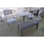 A wrought iron garden table, two chairs and a bench