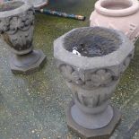 A pair of stone carved garden pots on pedestals
