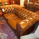 A Chesterfield two seater sofa upholstered in buttoned tan leather with brass studded detail