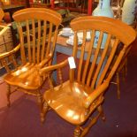 A set of four honey oak dining chairs including two carvers raised on turned stretchered supports