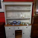 A painted pine kitchen dresser with open plate racks above arrangement of drawers and cupboards