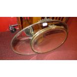 An Art Deco looking glass with oval bevelled plate and a similar brass framed mirror [2]