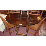 An antique oak drop flap dining table raised on turned gateleg supports