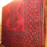 A hand knotted Afghan rug the red field with repeating black motifs