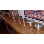 A collection of seven copper cooking pots and pans of graduating size