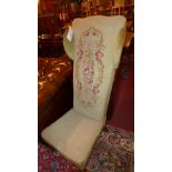 A Victorian prie dieu upholstered in floral needle point fabric on turned supports and castors