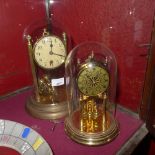 Two brass clocks under glass domes