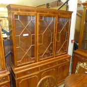 A yewood bookcase with triple glazed panel doors over drawers and panels on bracket feet