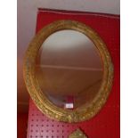 An oval gilt framed looking glass