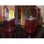 A pair of cranberry glass and silver plated biscuit barrells