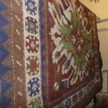 A Kazak carpet with two geometric medallions on a chocolate field, surrounded by four borders