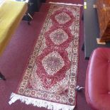 A Persian Kum style runner the rouge field with gold floral decoration in a multi borders