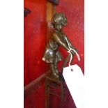 A small bronze of a child standing on a chair