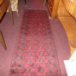 A hand knotted Afghan runner the rouge field with repeating black motifs