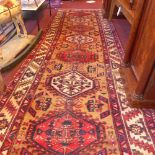 A Persian hand knotted Heriz runner the biege field with central pendant medallions in a triple