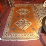 A Kazak carpet with two diamond lozenges on an orange field, surrounded by three borders