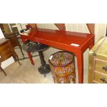 A red lacquered console table on tapered