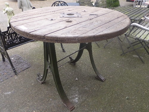 An industrial wooden circular top table raised on cast iron base