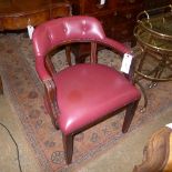 A chair upholstered in red button leather having mahogany frame