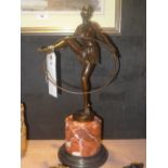 A bronzed figure of a dancer with hoop