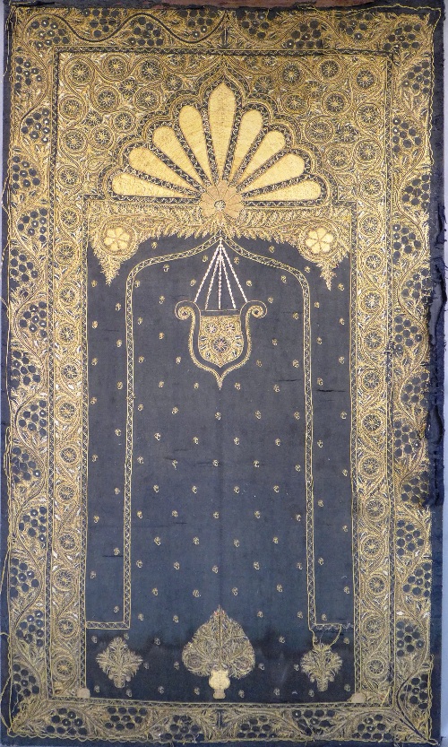 An Indian needlework panel, the black fabric decorated with gold coloured thread depicting a