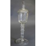 A C17th style engraved glass lidded goblet, the domed cover above foliate decorated bowl on a