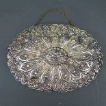 A Turkish silver mirror, the oval shaped back with embossed sunburst floral design, complete with